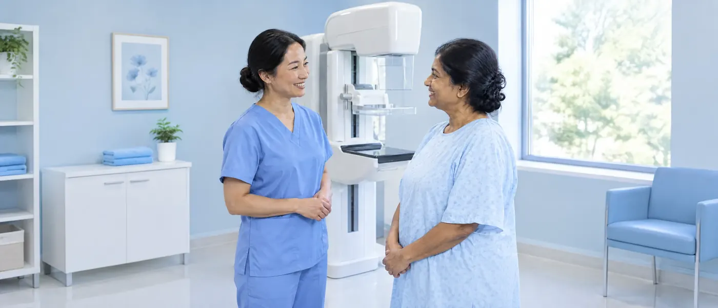 A technologist talking with a patient beside a mammography machine